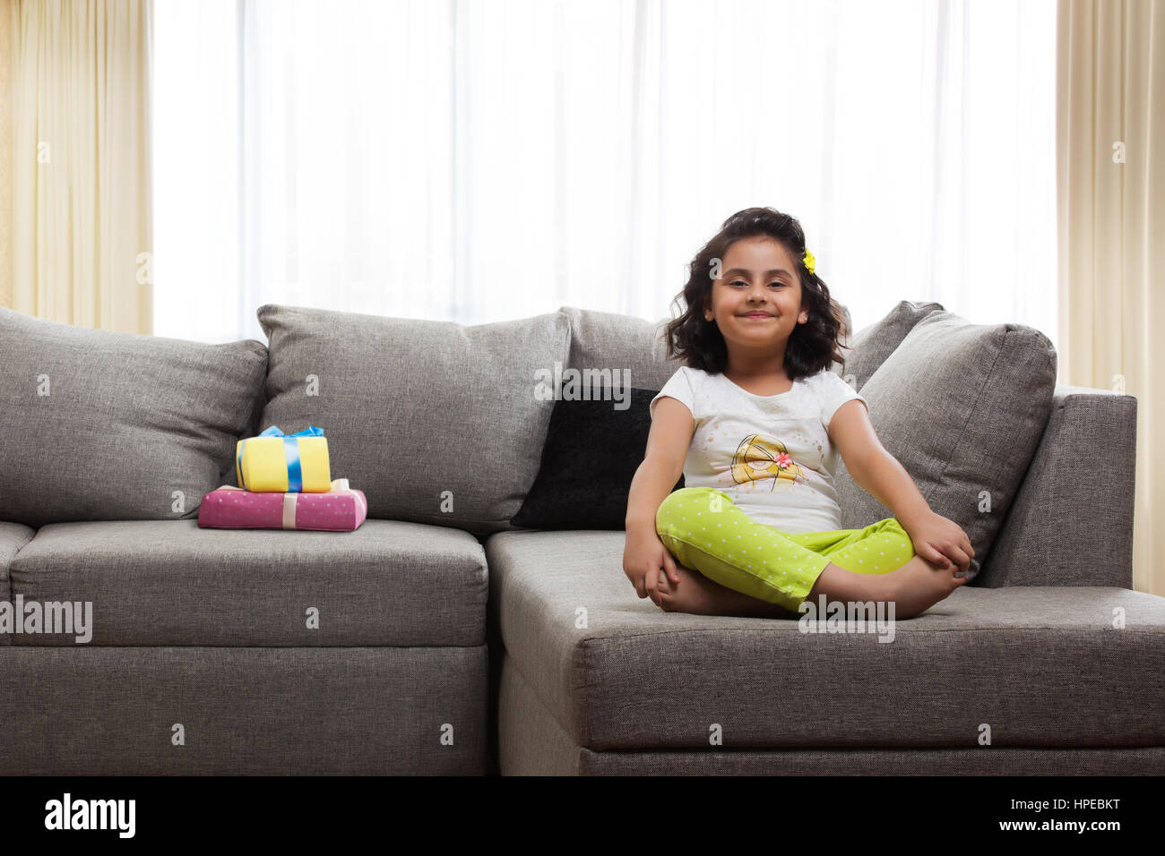 Sorridente ragazza seduta con le gambe incrociate sul divano Foto Stock