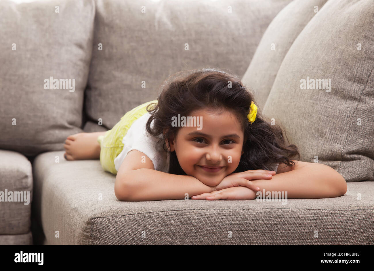 Sorridente bambina è rilassante sul divano Foto Stock