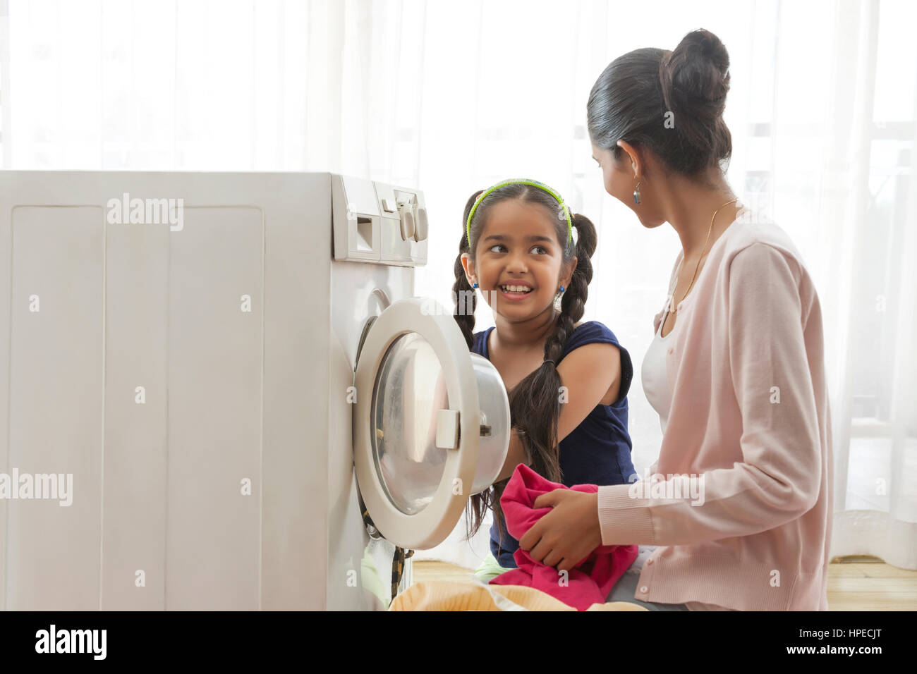 Sorridente madre e figlia di caricamento della macchina di lavaggio Foto Stock