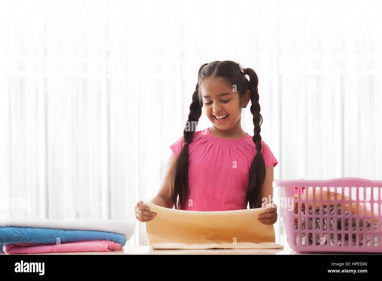 Ragazza sorridente lavanderia di piegatura Foto Stock