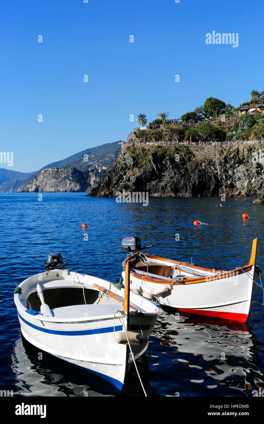 Due piccole barche da pesca ancorate e galleggia in una calma il mare blu vicino alla costa di Manarola, Cinque Terre, Italia. Foto Stock