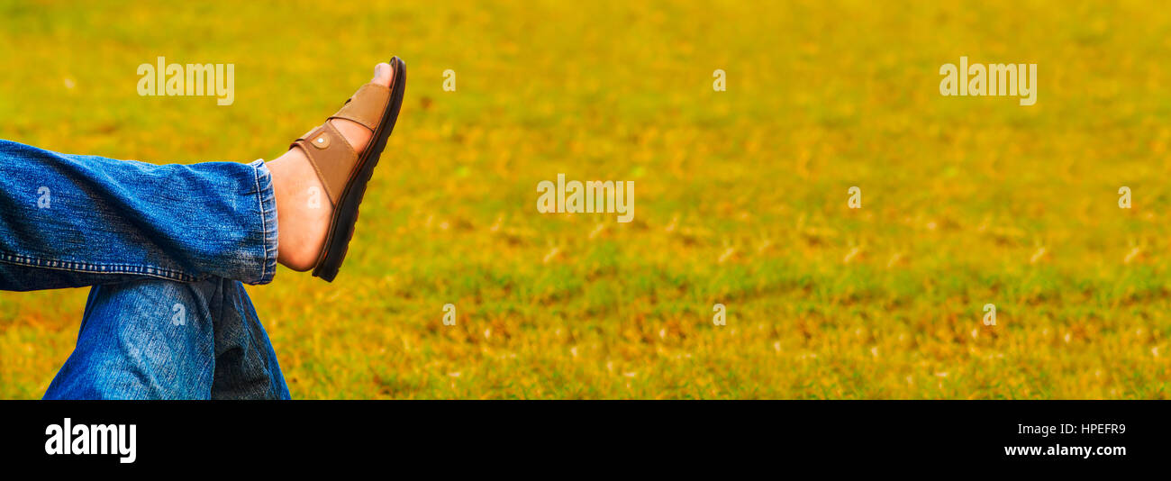 Adolescente spensierato giacente sul retro su erba e gambe incrociate a ginocchio in una libertà fotografia concettuale. Foto Stock
