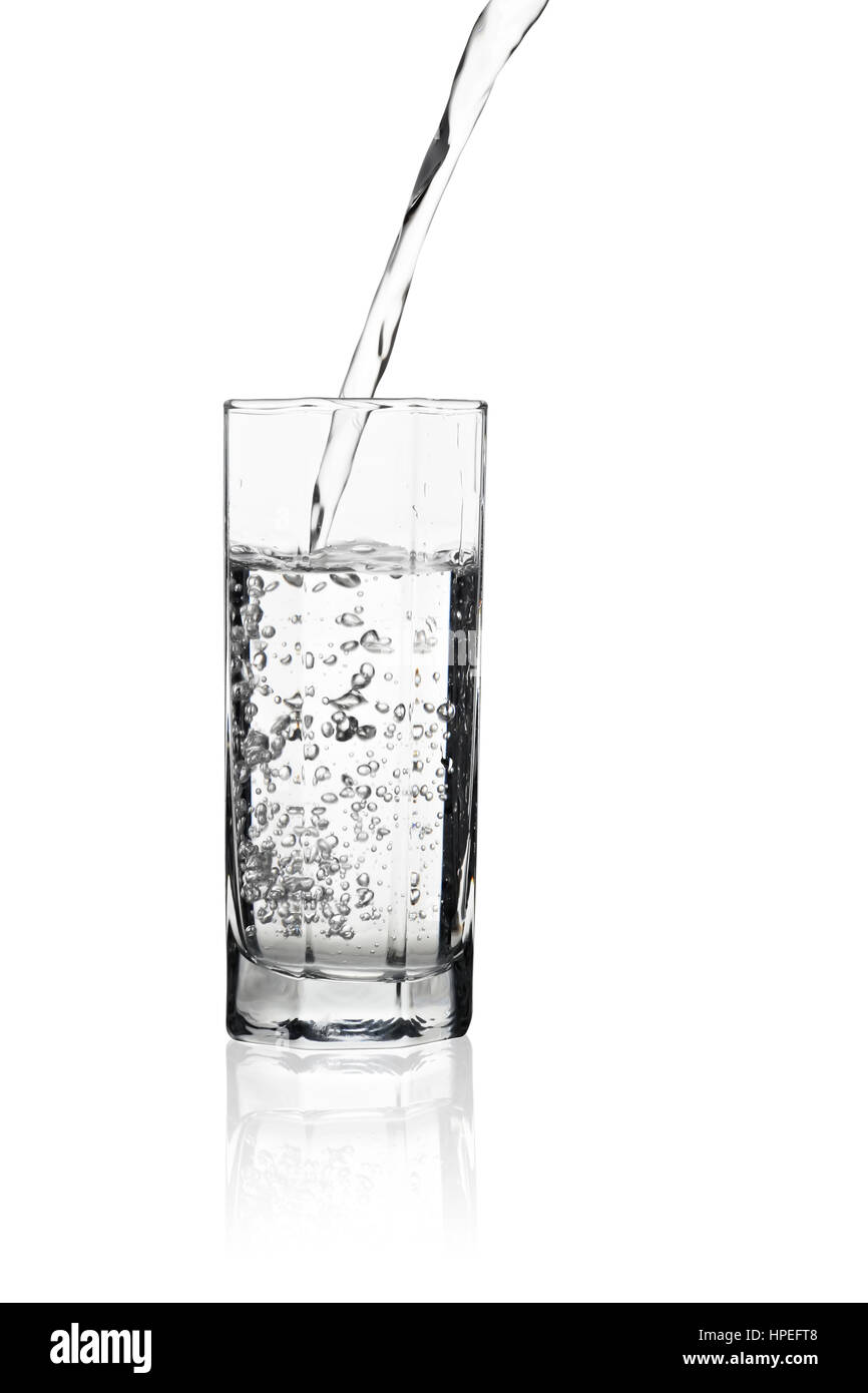 Versare acqua in un bicchiere alto con bolle di aria nell'acqua e di riflessione sul tavolo isolato su sfondo bianco Foto Stock
