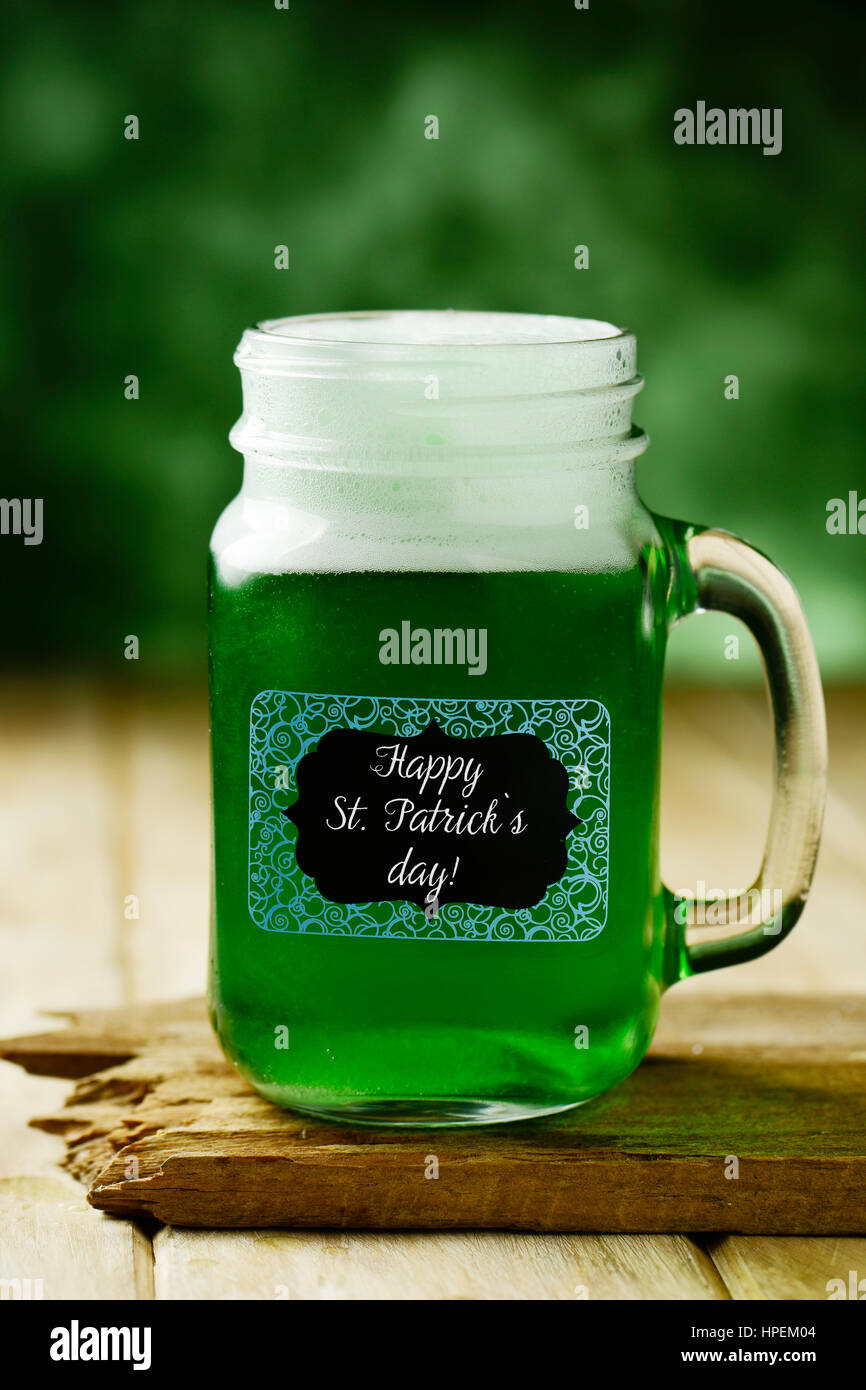 Primo piano di un muratore jar con tinta verde birra e il testo happy saint patricks giorno scritto in una etichetta attaccata ad essa, su una tavola di legno superficie rustico Foto Stock