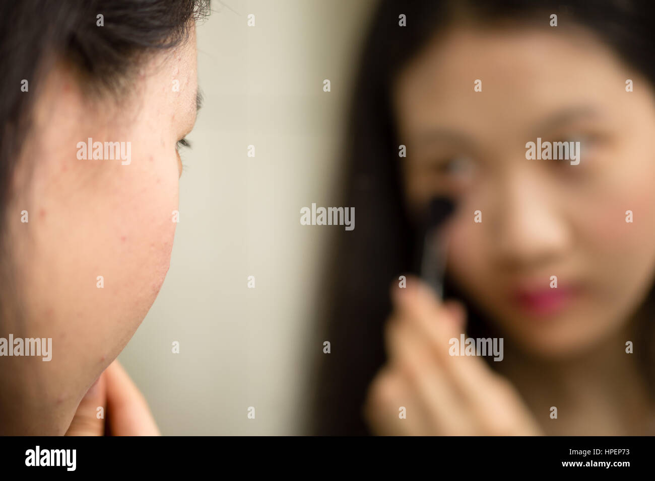 Adolescente cinese a mettere su il trucco con spazzola nella parte anteriore dello specchio Foto Stock