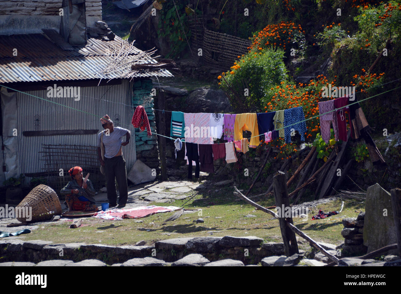 Il contadino e sua moglie guardando il lavaggio appeso sulla linea di abbigliamento nel villaggio di Banthanti nel Santuario di Annapurna Himalaya,, Nepal, Asia Foto Stock