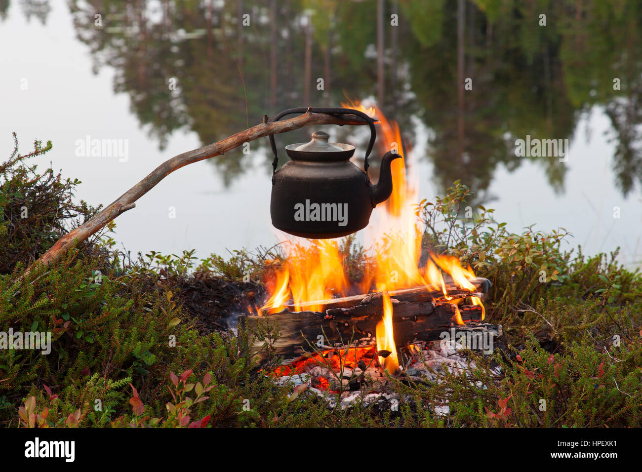 Stagno annerito Bollitore acqua bollente su fiamme dal fuoco durante la passeggiata lungo il lago Foto Stock