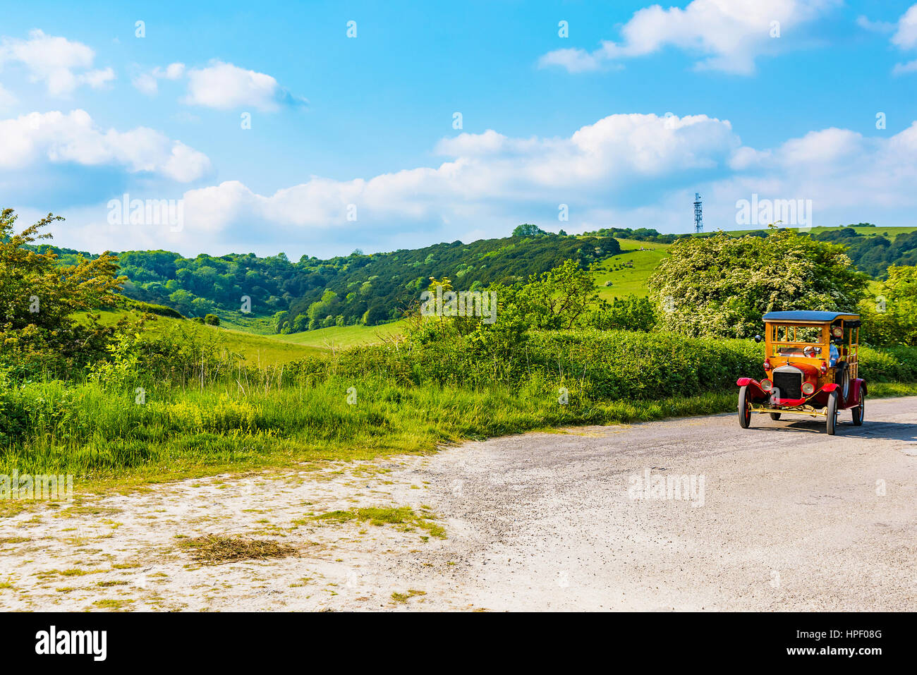 Vecchio British auto guidando lungo una strada di campagna in una giornata di sole Foto Stock