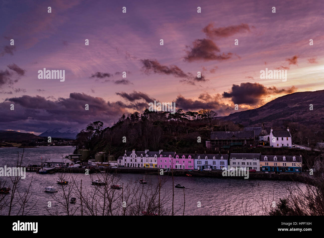 La fila di case colorate sulla banchina del porto di Portree, Isola di Skye in Scozia. Raggi del sole attraverso le nuvole a strati, con Cuillin Hills in background. Foto Stock