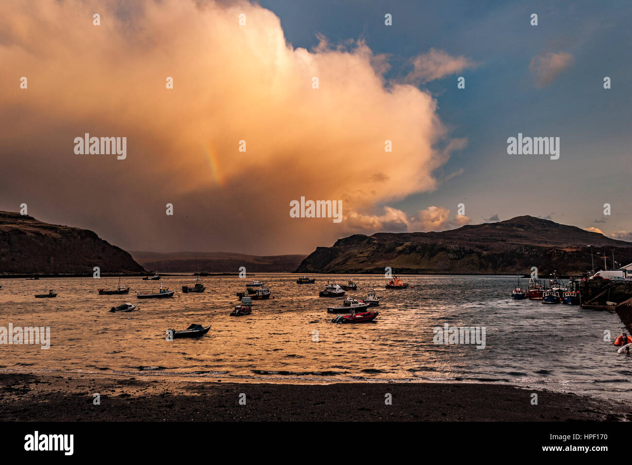 Vista del suono Rassay dalla banchina del porto di Portree, Isola di Skye in Scozia, come il sole stava andando per la sera. Il sole arancione riflettente. Foto Stock