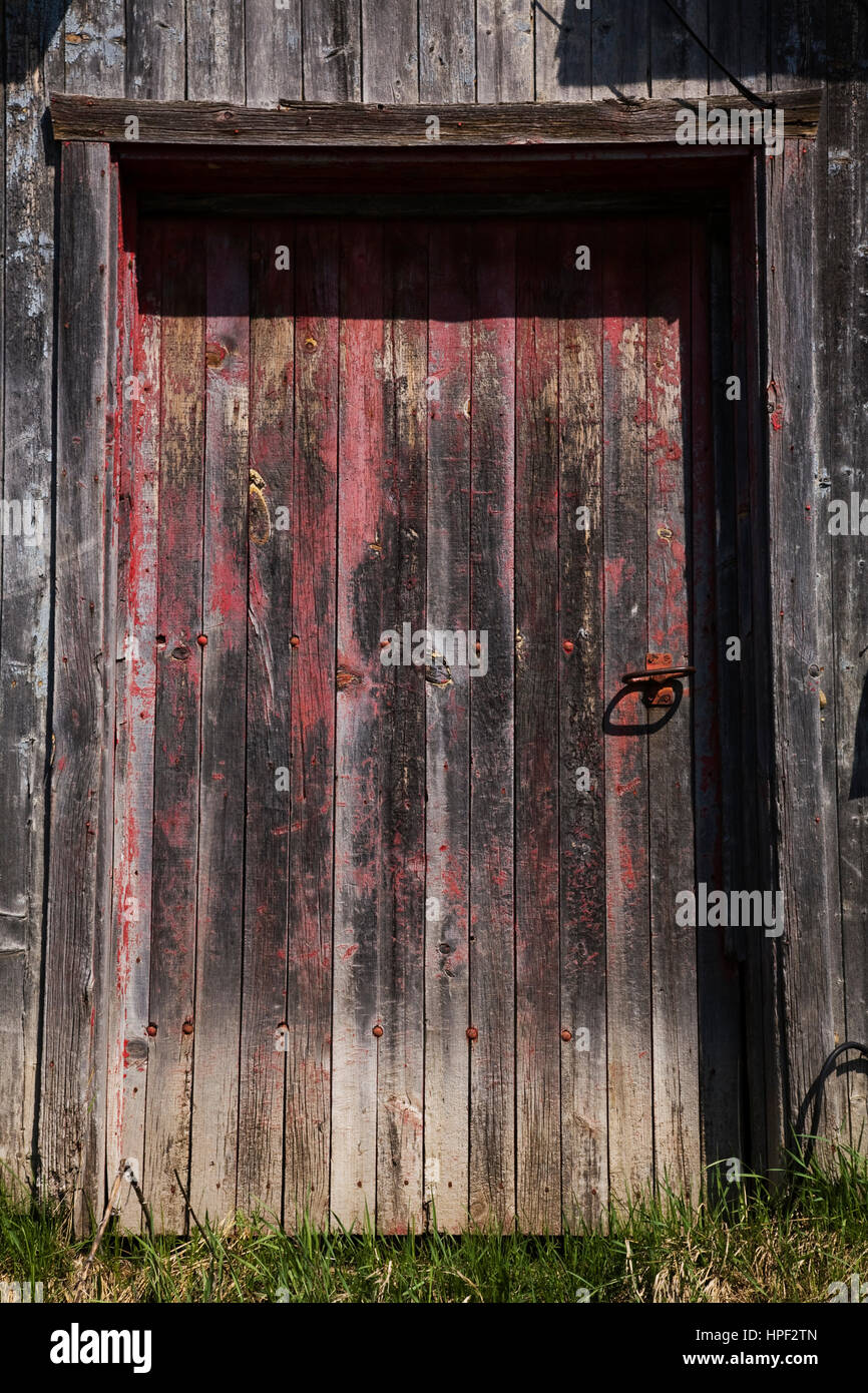 Close-up di vecchio rosso sbiadito fienile in legno porta. Foto Stock