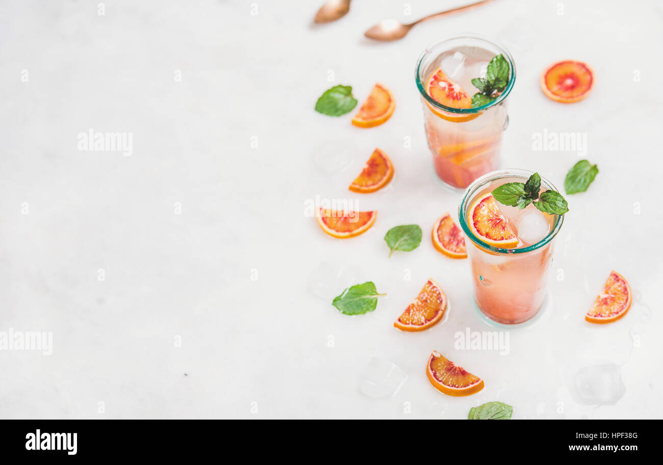 Arancio sanguigno estate fresca limonata fatta in casa con ghiaccio e menta in bicchieri, grigio chiaro sfondo marmo, il fuoco selettivo, copia di spazio orizzontale, Campos Foto Stock