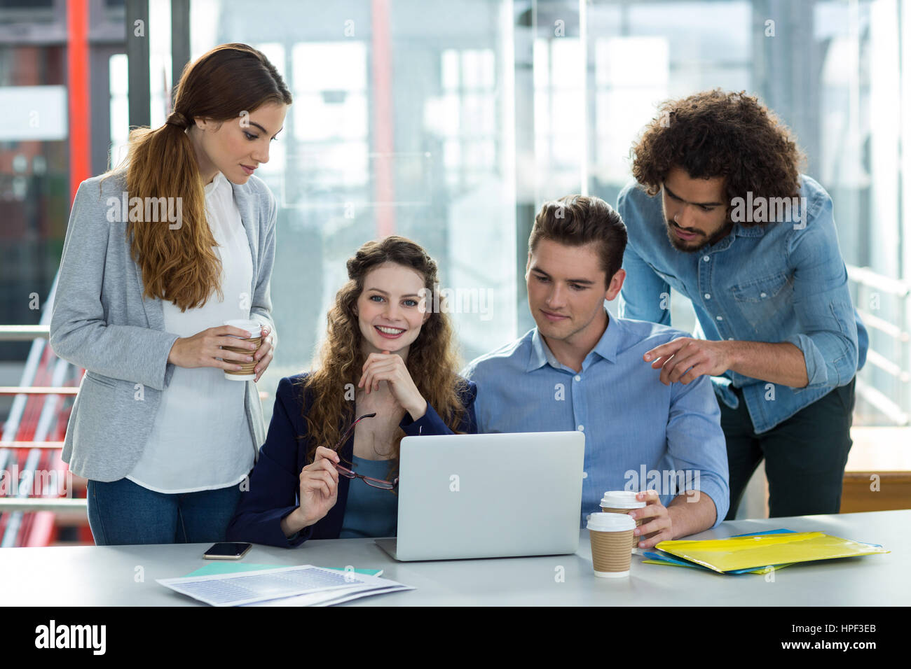 Sorridente team business discutendo su laptop in riunione in ufficio Foto Stock