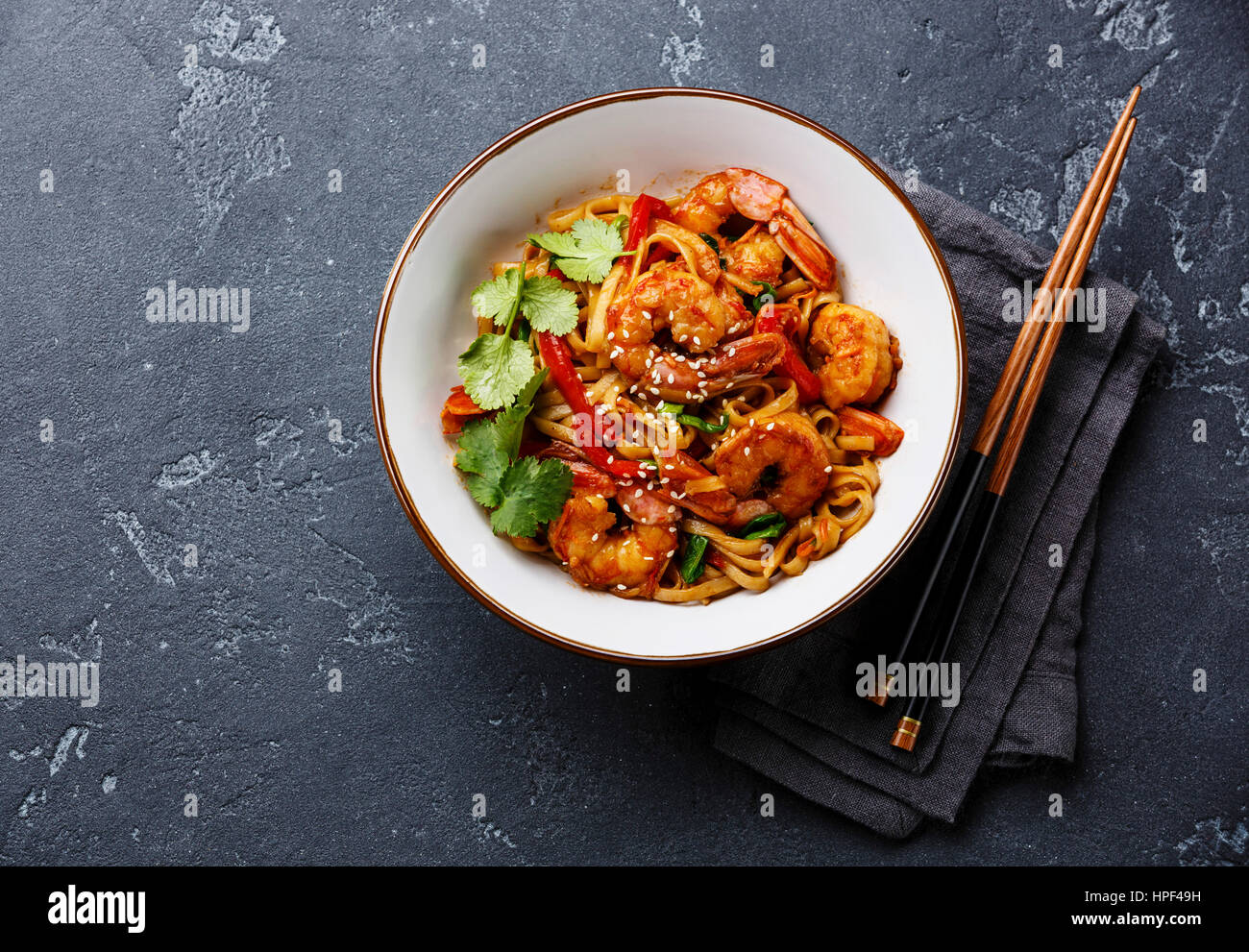 Udon friggere gli spaghetti con i gamberi in una terrina e bacchette in pietra scura di sfondo spazio di copia Foto Stock