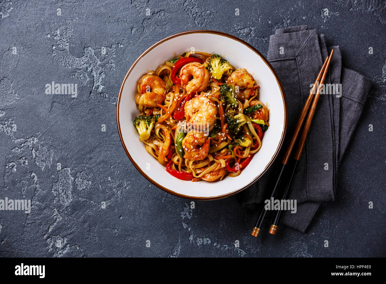 Udon friggere gli spaghetti con i gamberi in una terrina e bacchette in pietra scura di sfondo spazio di copia Foto Stock