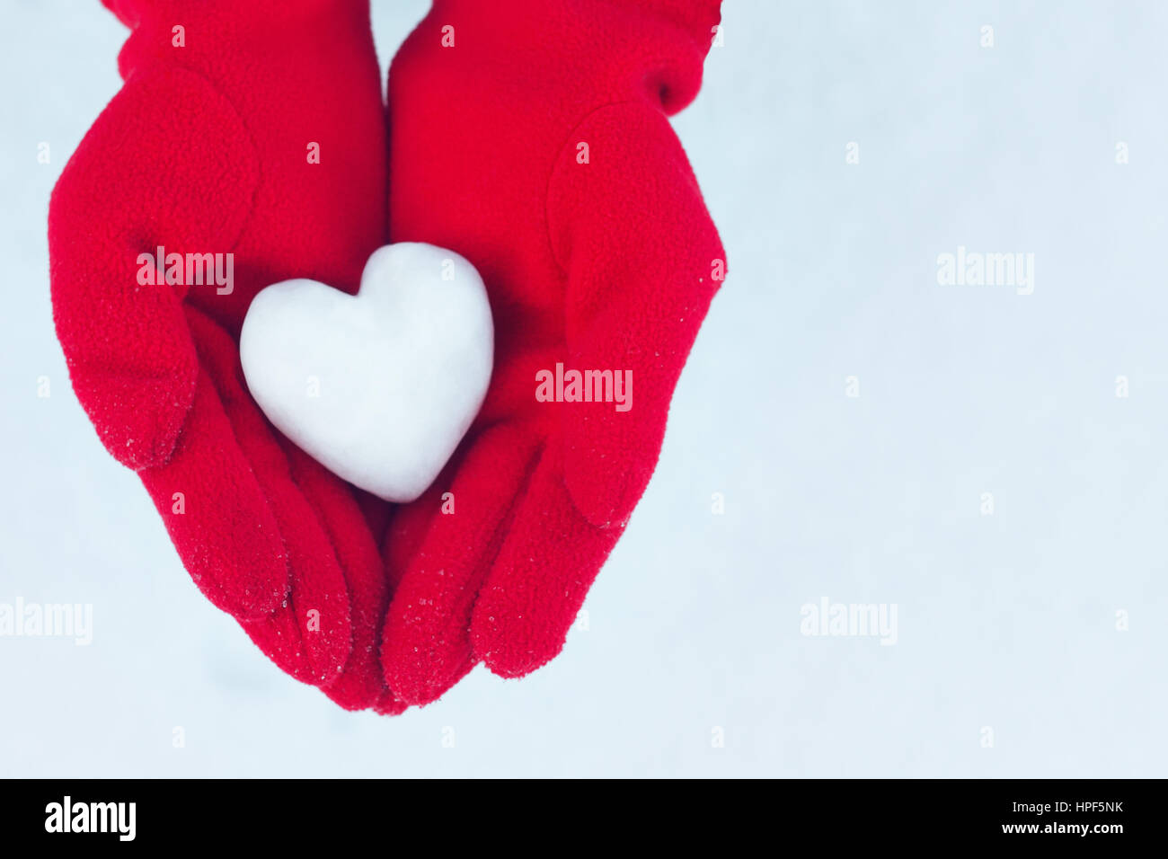 Cuore di neve nelle mani. Red guanti d'inverno. Il concetto di amore. Il  giorno di San Valentino biglietto di auguri con copia spazio. Sfondo di San  Valentino. Donna con le mani in