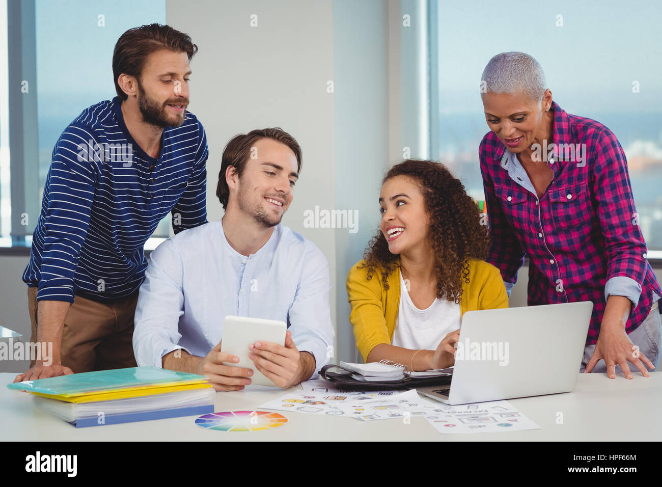 Il team di progettisti grafici discutendo su computer portatile in ufficio Foto Stock
