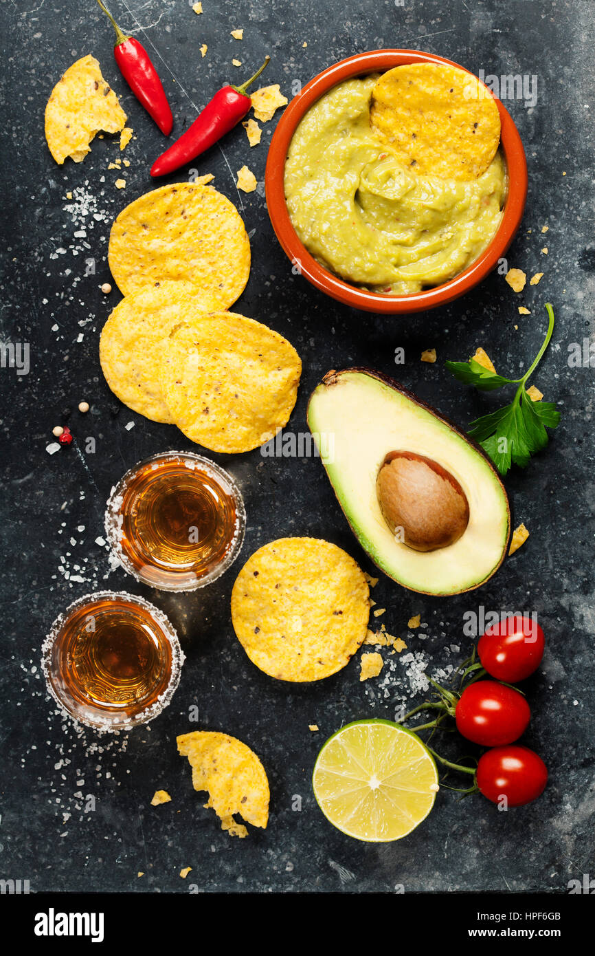 Ciotola di nachos messicani con chip in casa fresca salsa guacomole e tequila scatti sopra il vecchio sfondo. Vista dall'alto. Con spazio per il testo Foto Stock