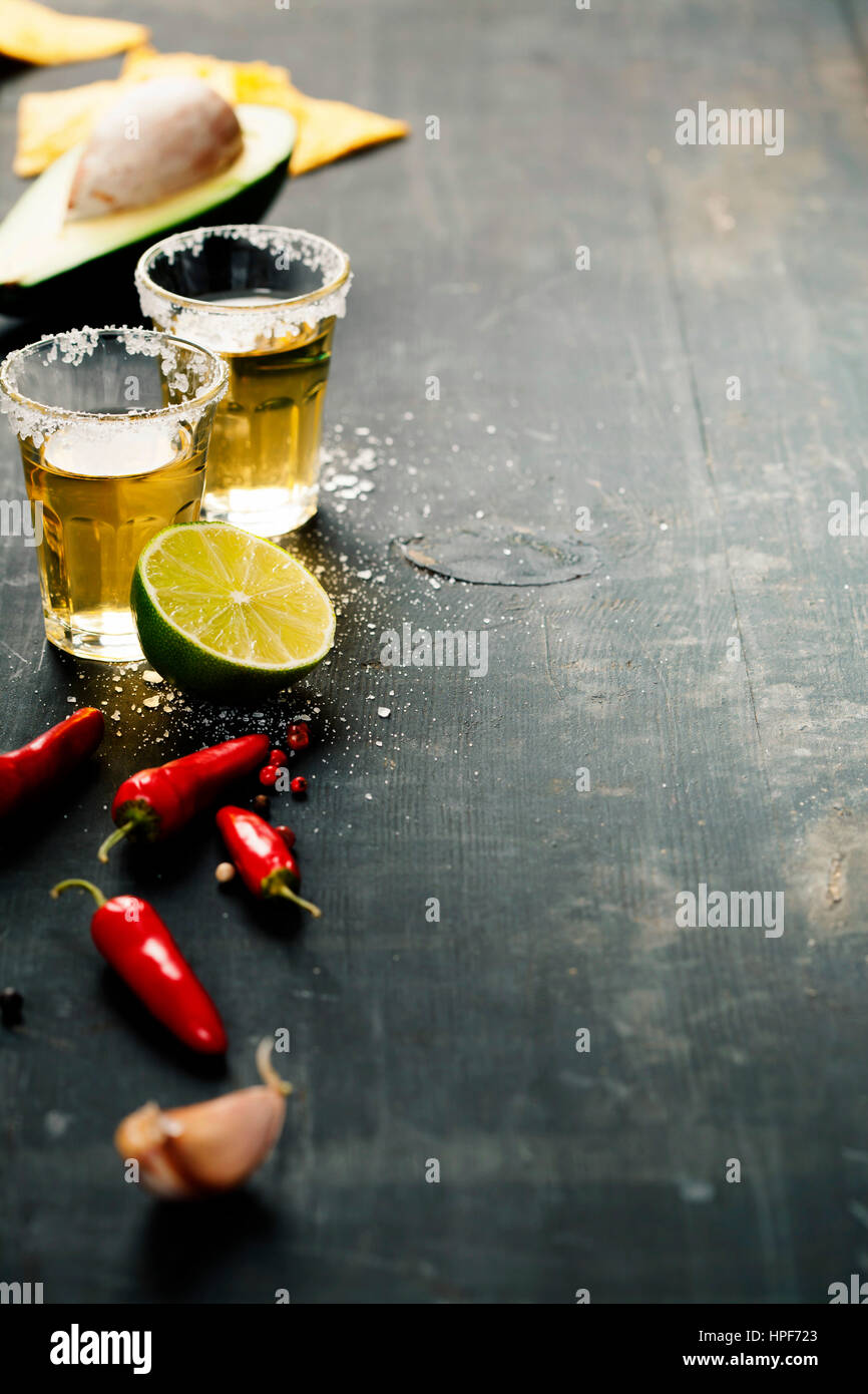 Scatti di tequila e ingredienti messicani sul tavolo rustico Foto Stock