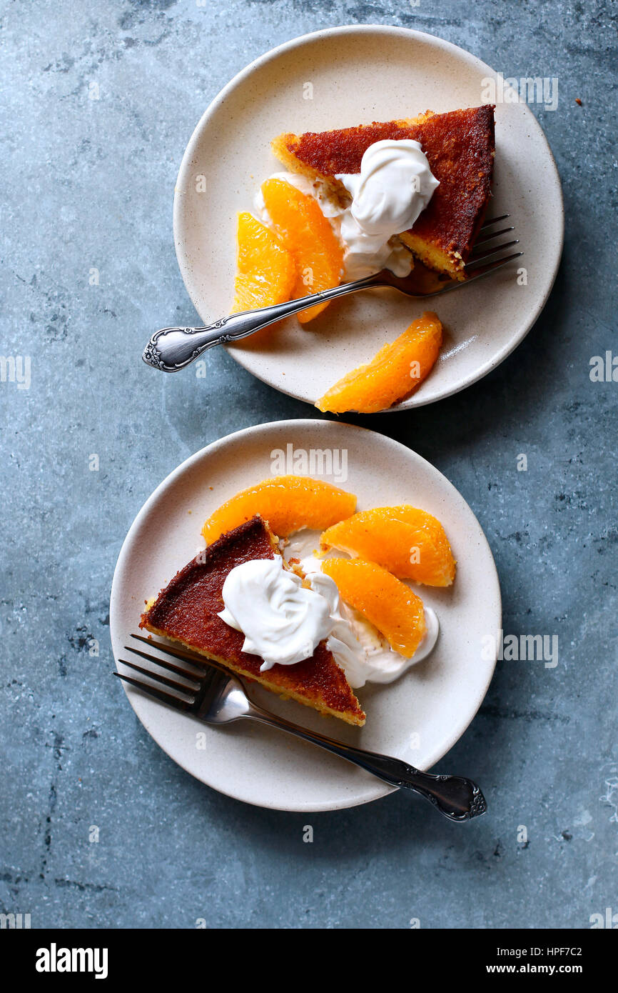 Polenta arancione fette di torta su un piatto servito con creme fraiche e succo di arancia Foto Stock