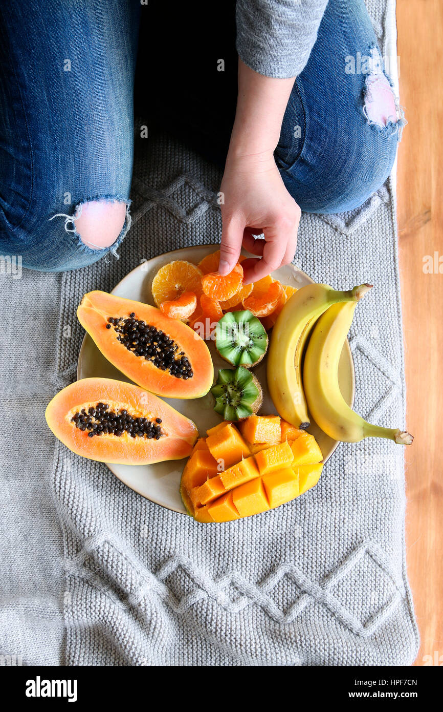 Donna seduta sul letto e servire frutta fresca.vista superiore Foto Stock