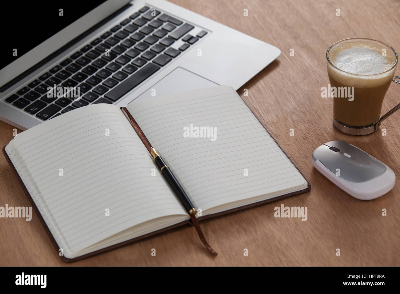Tazza di caffè con il computer portatile, un mouse, una penna e agenda  elettronica su sfondo di legno Foto stock - Alamy