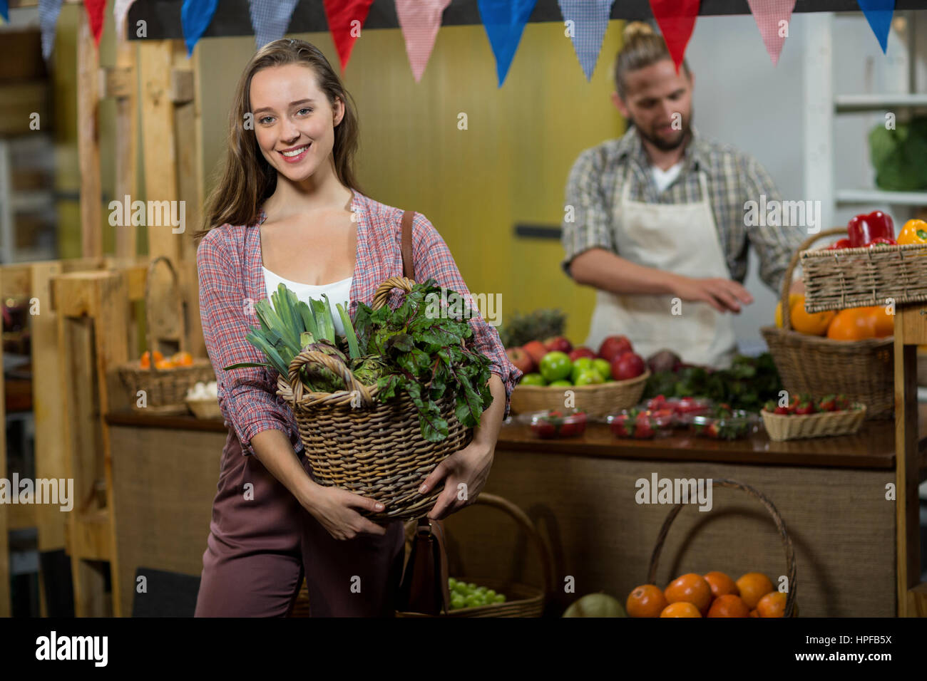 Ritratto di donna sorridente cestello di contenimento di verdure a foglia verde nel negozio di alimentari Foto Stock