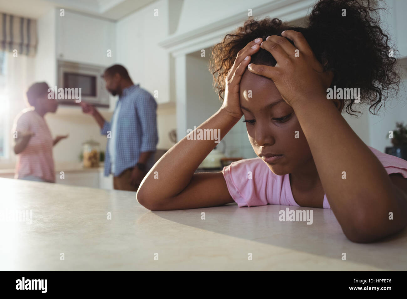 Ragazza triste ascoltando i suoi genitori sostenendo in cucina a casa Foto Stock