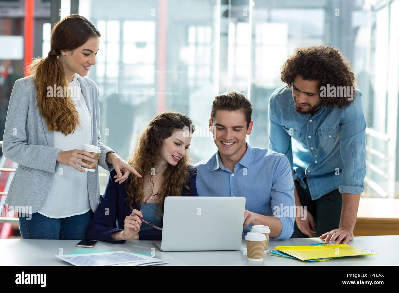 Sorridente team business discutendo su laptop in riunione in ufficio Foto Stock