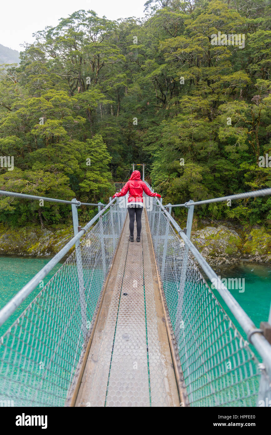Donna attraversando ponte di sospensione, blu Piscine, Haast Pass, West Coast, a Southland, Nuova Zelanda Foto Stock