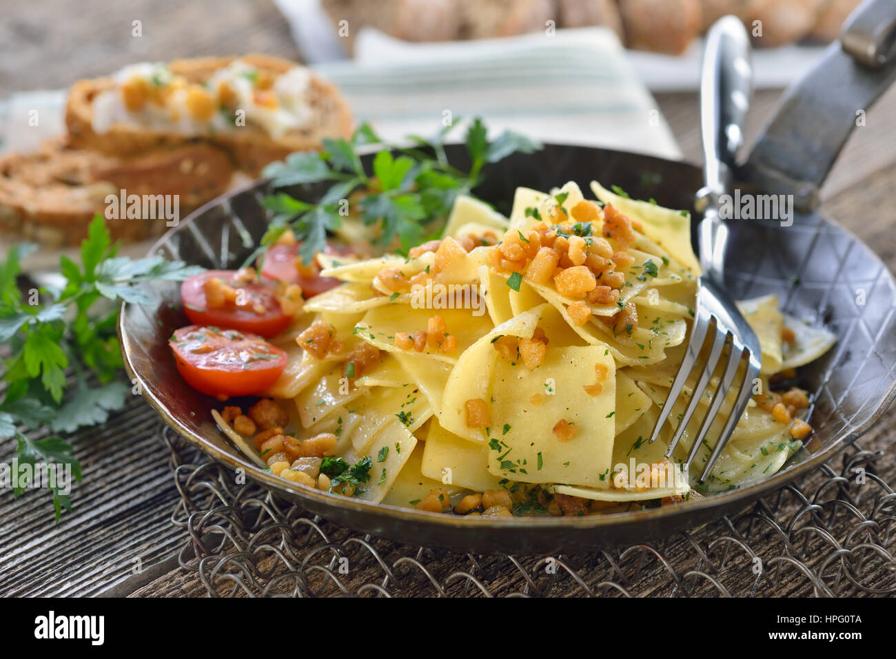 La cucina austriaca: arrosto a forma di quadrato di pasta con pancetta ciccioli (cosiddetto "Grammelfleckerl') servita in un ferro da stiro a padella, pane di segale con crackli Foto Stock