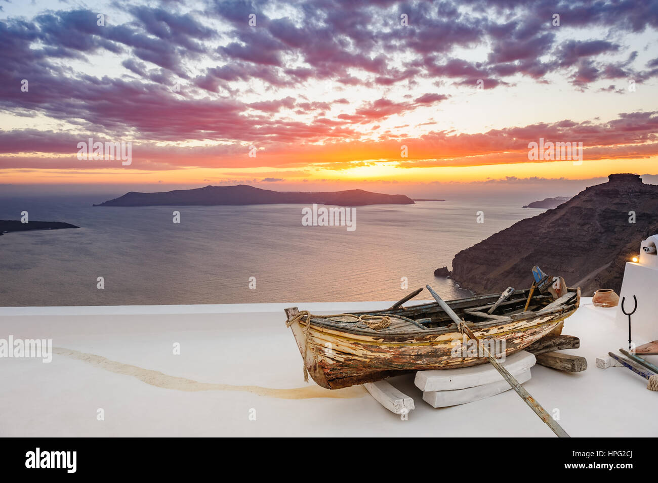 In legno antico fishermans''s barca su roofof house di Firostefani village con la tipica architettura di bianco, isola di Santorini, Grecia, durante il tramonto sul mare Foto Stock