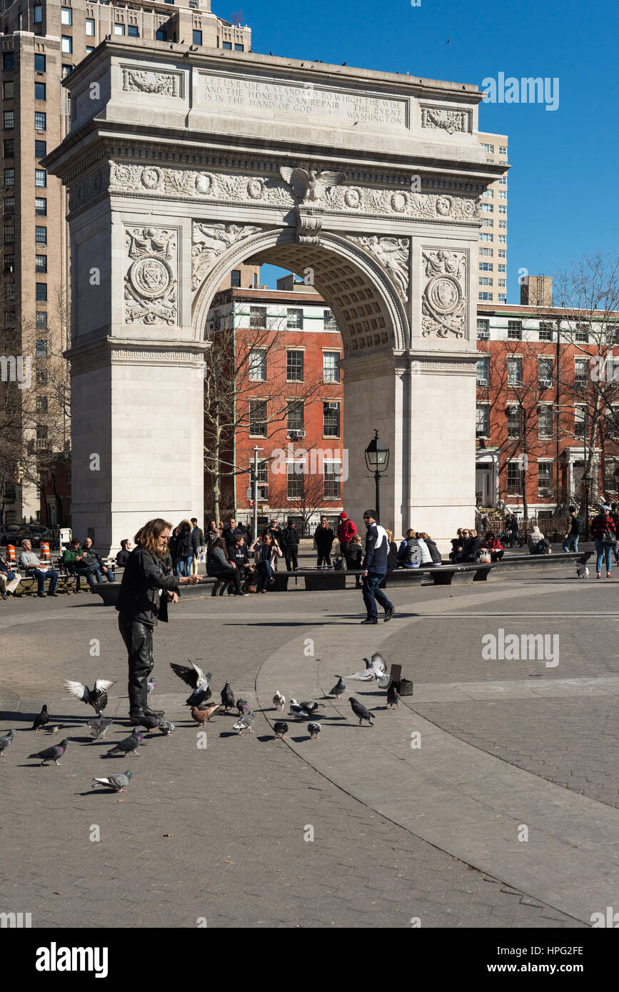 Un uomo gioca con piccioni in Washington Square Park di New York City, New York, Stati Uniti d'America Foto Stock