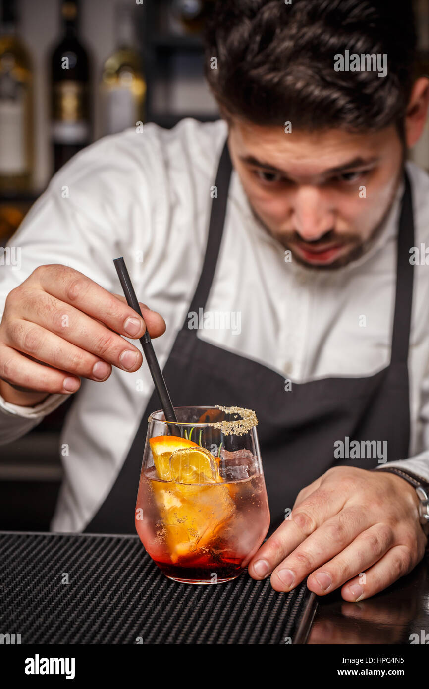 Barman mettendo la paglia in cocktail sul bancone bar Foto Stock