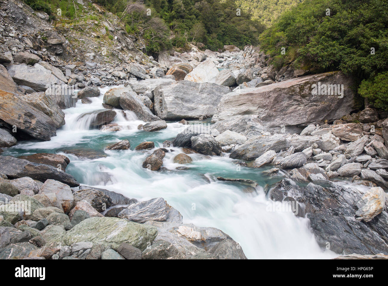 Haast Pass, montare gli aspiranti National Park, West Coast, Nuova Zelanda. La schiumatura acque del fiume Haast tumbling sulle rocce alle porte di Haast. Foto Stock