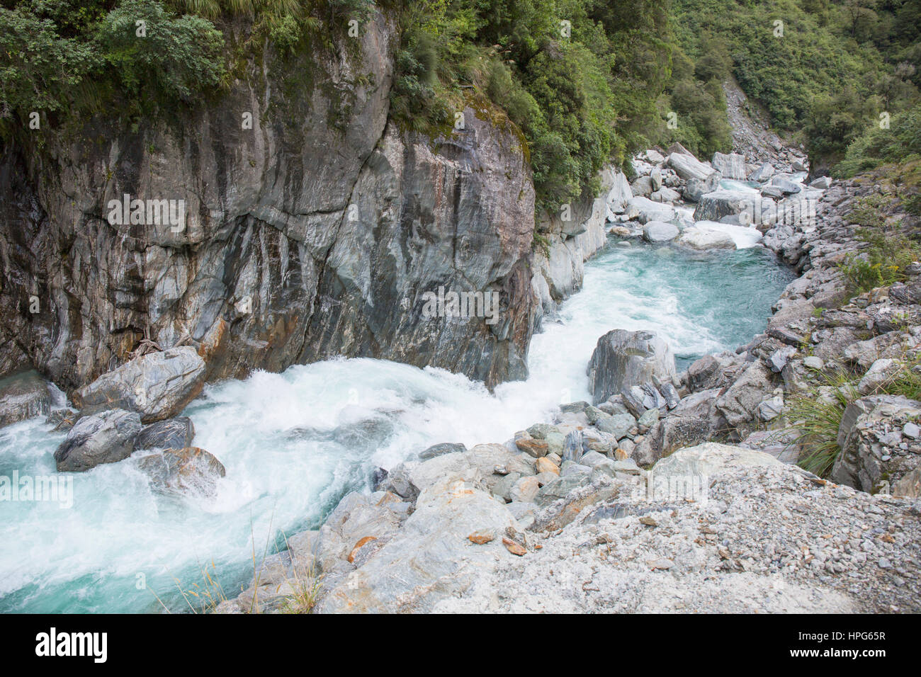 Haast Pass, montare gli aspiranti National Park, West Coast, Nuova Zelanda. La schiumatura acque del fiume Haast immergersi a valle alle porte di Haast. Foto Stock