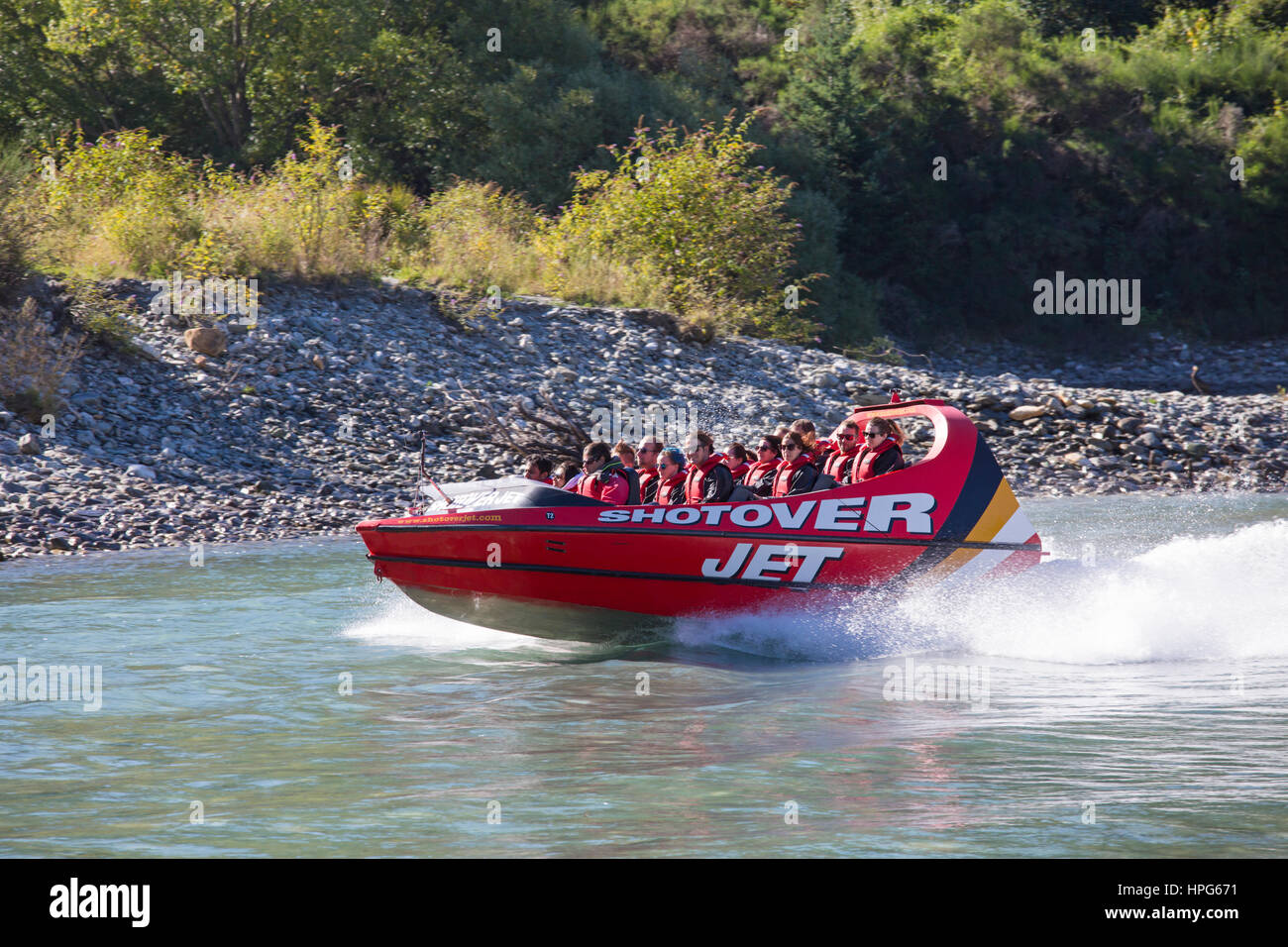 Queenstown, Otago, Nuova Zelanda. Shotover Jet Boat accelerando attraverso le acque turchesi e cristalline del fiume Shotover. Foto Stock