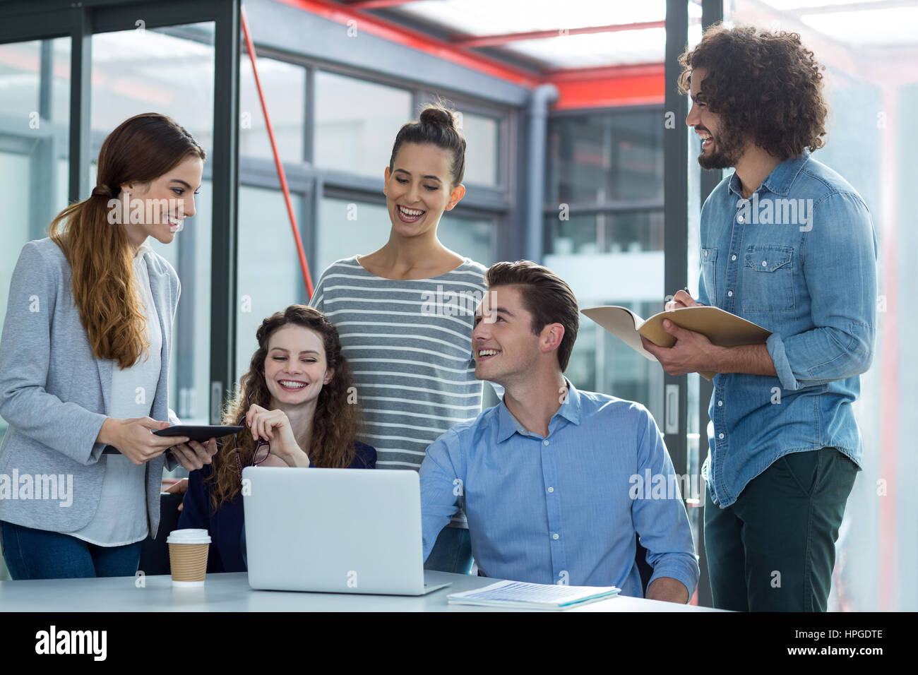 Sorridente team business discutendo su laptop in riunione in ufficio Foto Stock