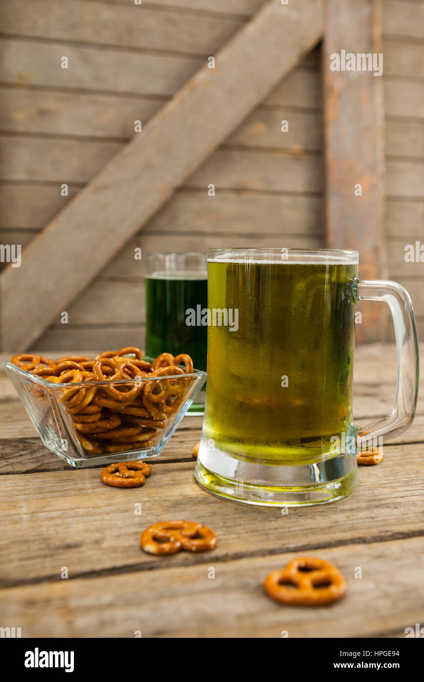 Il giorno di San Patrizio due boccali di birra con pretzel su una superficie di legno Foto Stock