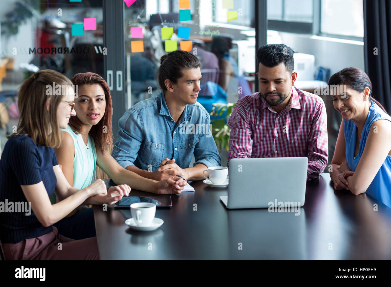 Sorridendo gli imprenditori aventi la discussione su computer portatile in ufficio Foto Stock