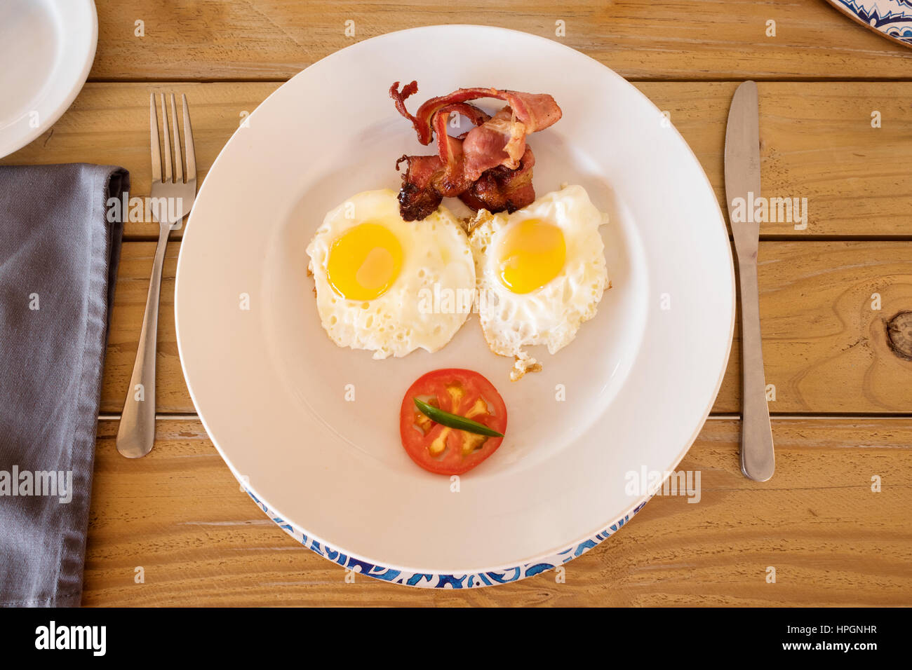 Una piastra di prima colazione servita in un accampamento in Namibia. Sulla piastra sono presenti due uova fritte, Sunny Side, alcuni bacon croccante e la metà di un pomodoro. Foto Stock