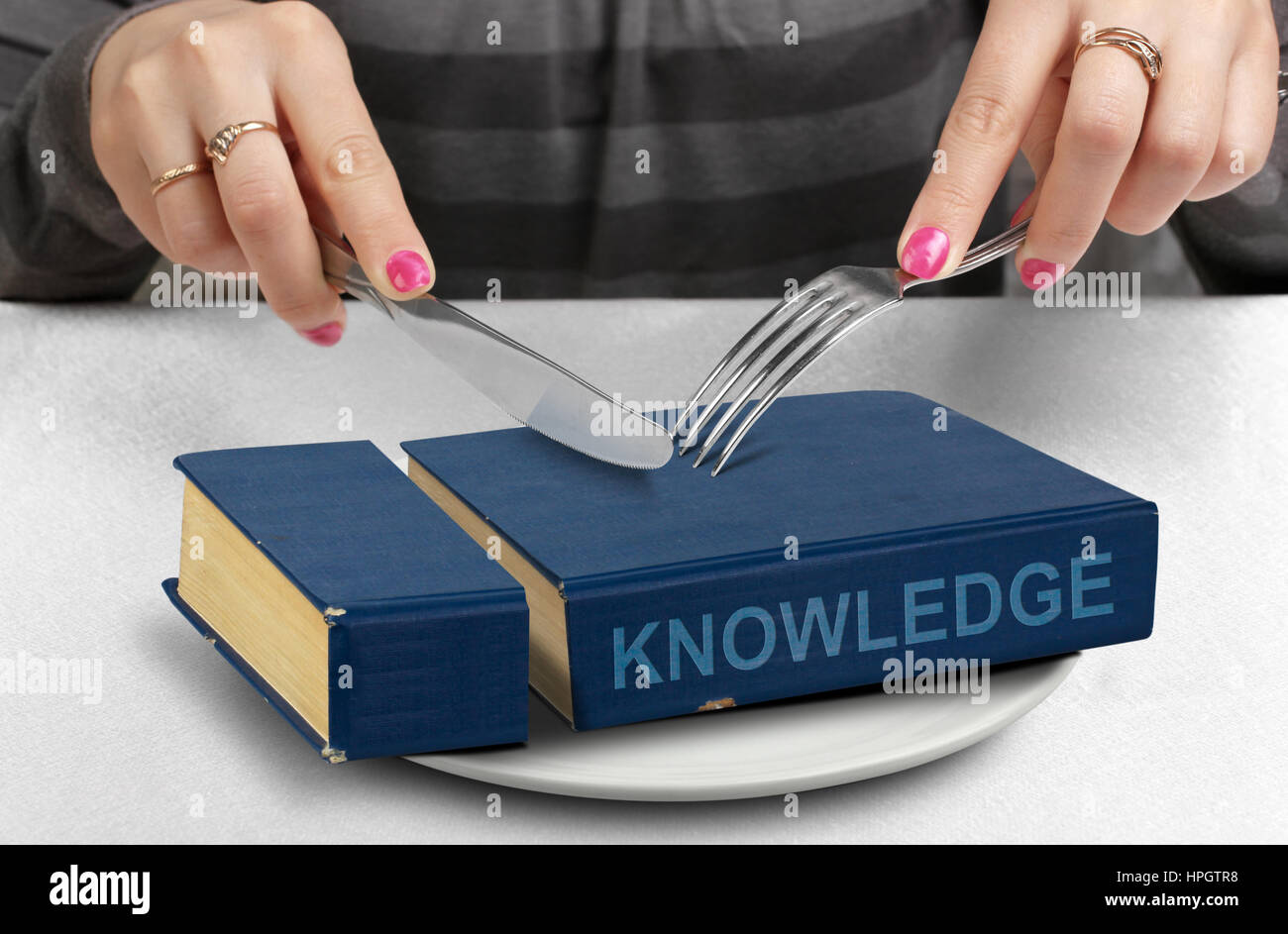 Consumare del concetto di conoscenza, tagliare il libro sulla piastra Foto Stock
