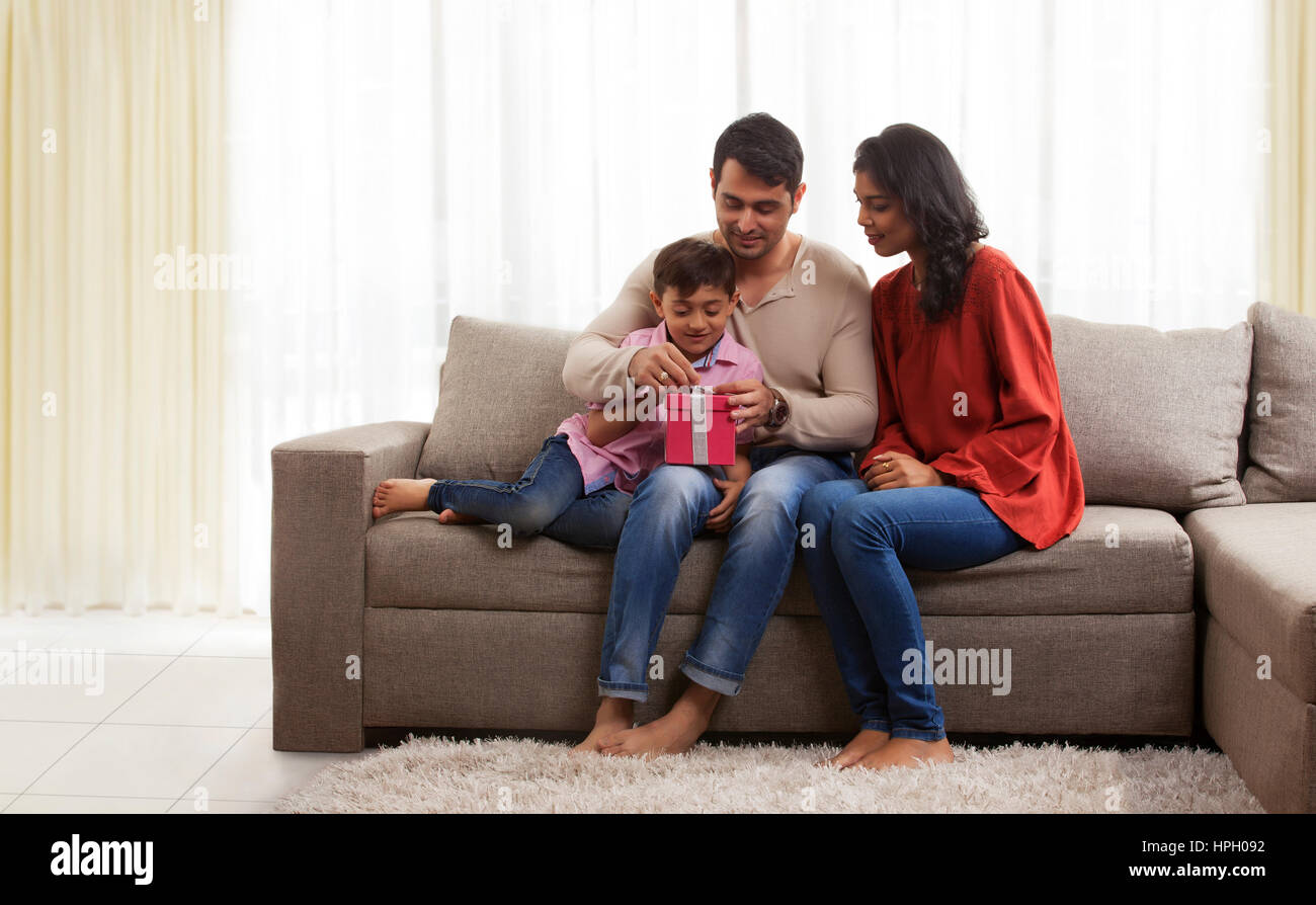 Sorridente genitori con figlio apertura confezione regalo Foto Stock