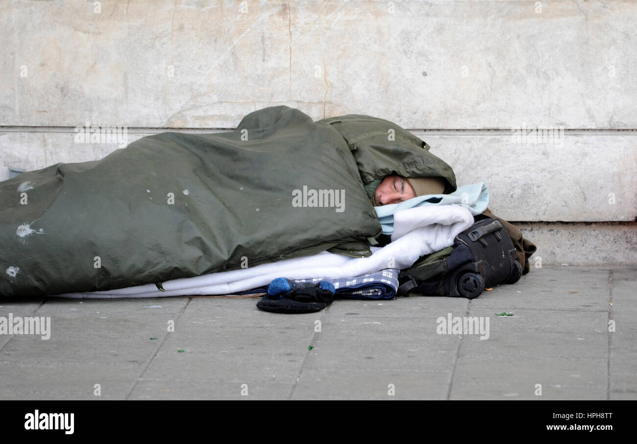 Senzatetto uomo dorme grezzo su strade di Brighton come passer da passeggiate passato Foto Stock