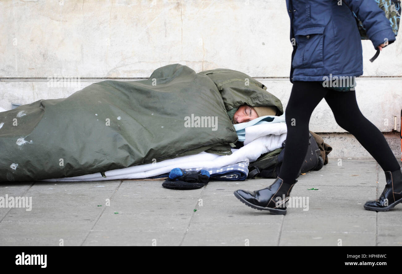 Senzatetto uomo dorme grezzo su strade di Brighton come passer da passeggiate passato Foto Stock