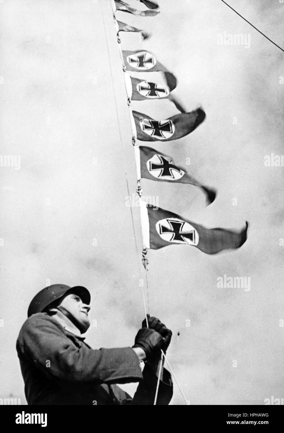 L'immagine della propaganda nazista mostra un pennant che viene innalzato presso una base di batteria costiera tedesca di Wehrmacht nella Francia occupata, per celebrare la sparatoria degli aerei britannici. Pubblicato nel dicembre 1941. Un reporter nazista ha scritto sul retro del quadro, 'batteria di artiglieria marina di successo. Pieno di orgoglio, un artigliere marino alza il pennante sull'albero. Dopo l'acquisizione della base di batteria sono stati realizzati quattordici tiri di successo presso i britannici.» Fotoarchiv für Zeitgeschichte - NESSUN SERVIZIO DI CABLAGGIO - | utilizzo in tutto il mondo Foto Stock