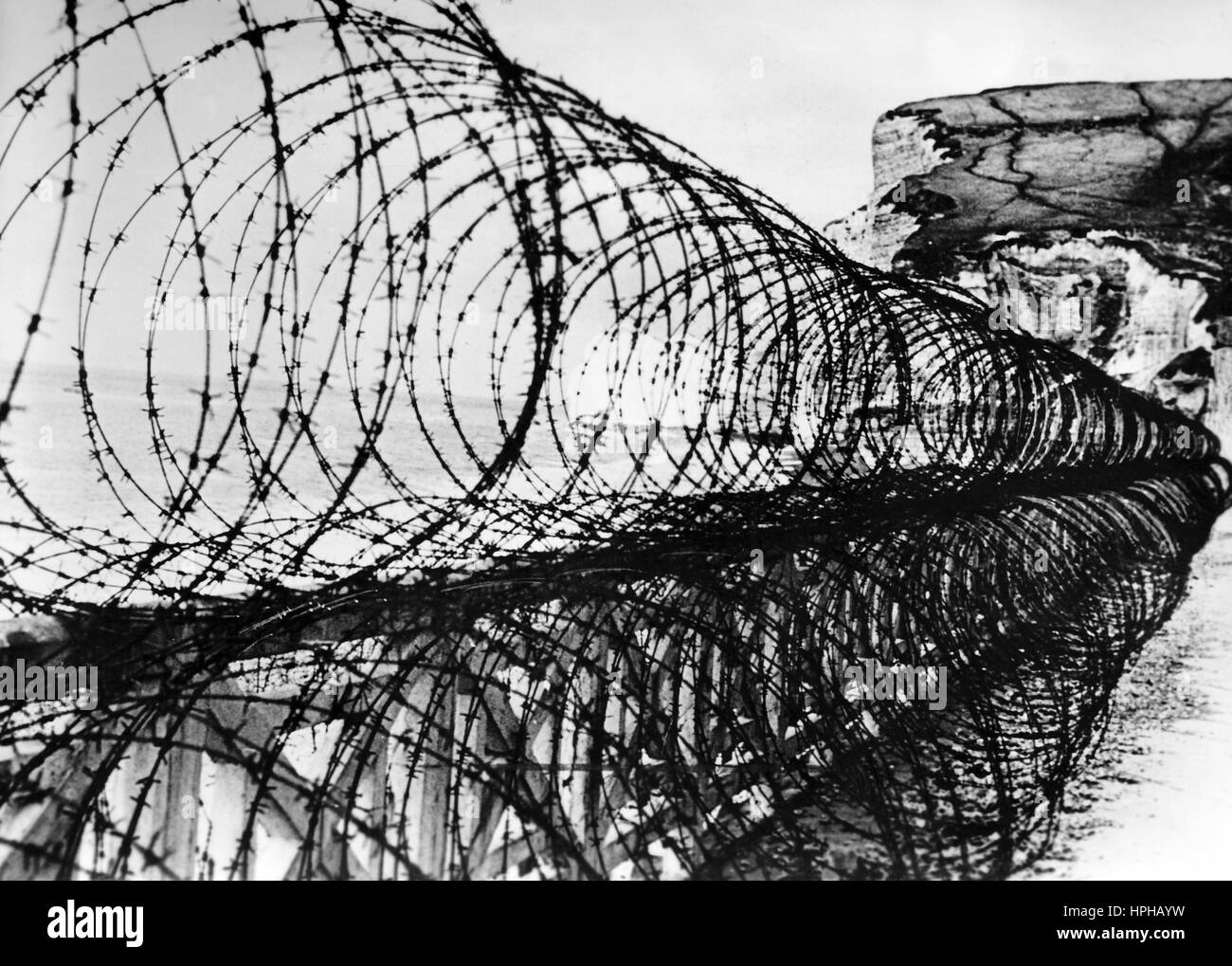 La propaganda nazista immagine mostra un tedesco della Wehrmacht sulla base Atlantic Wall protetti da un recinto di filo spinato. Pubblicato in aprile 1943. [Vedere anche PA 82343768.] un nazista reporter ha scritto sul retro della foto su 16.04.1943, "un inespugnabile roccaforte di acciaio e calcestruzzo: Atlantic Wall. Alle porte dell' Europa occidentale gli ingegneri e gli uomini da organizzazione Todt ha creato queste grandi fortificazioni che noto insieme come Atlantic Wall rappresentano il più grande sistema di merli di tutti i tempi. Questi filo spesso barriere sono ubicati in tutta la costa atlantica, formando un imprendibile de Foto Stock