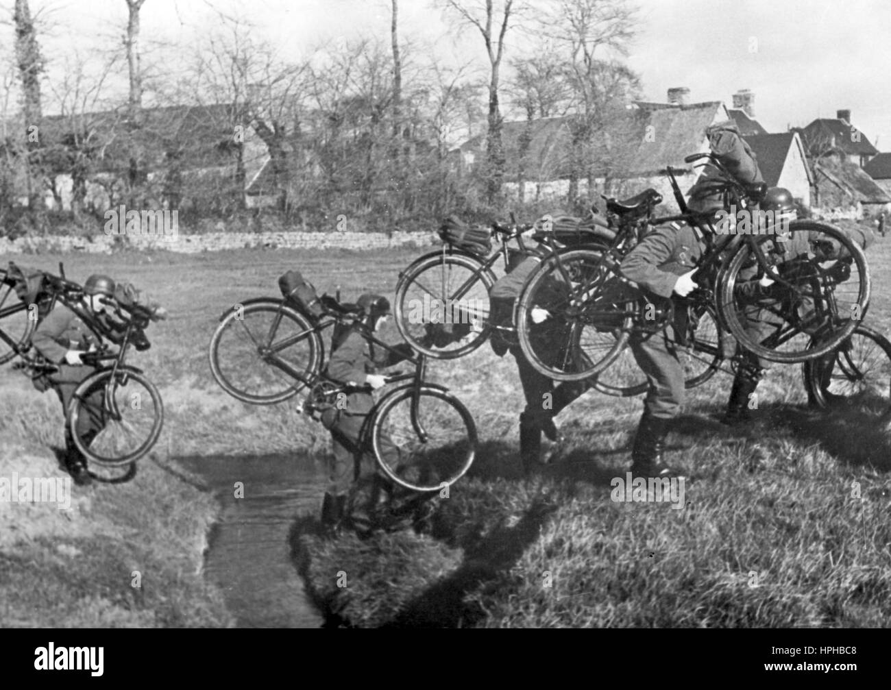 L'immagine della propaganda nazista mostra i membri di una truppa tedesca di biciclette Wehrmacht su un esercizio di allenamento. Pubblicato nel gennaio 1941. Un reporter nazista ha scritto sul retro della foto su 02.01.1941, 'attraverso esercizi continui, il potere dei nostri soldati è aumentato. Uno squadrone di bicicletta in allenamento. Ogni ostacolo deve essere affrontato. Parete, recinzione o ruscello." Fotoarchiv für Zeitgeschichte - NESSUN SERVIZIO DI CABLAGGIO - | utilizzo in tutto il mondo Foto Stock L'immagine della propaganda nazista mostra i membri di una truppa tedesca di biciclette Wehrmacht su un esercizio di allenamento. Pubblicato nel gennaio 1941. Un reporter nazista ha scritto sul retro della foto su 02.01.1941, 'attraverso esercizi continui, il potere dei nostri soldati è aumentato. Uno squadrone di bicicletta in allenamento. Ogni ostacolo deve essere affrontato. Parete, recinzione o ruscello." Fotoarchiv für Zeitgeschichte - NESSUN SERVIZIO DI CABLAGGIO - | utilizzo in tutto il mondo Foto Stock