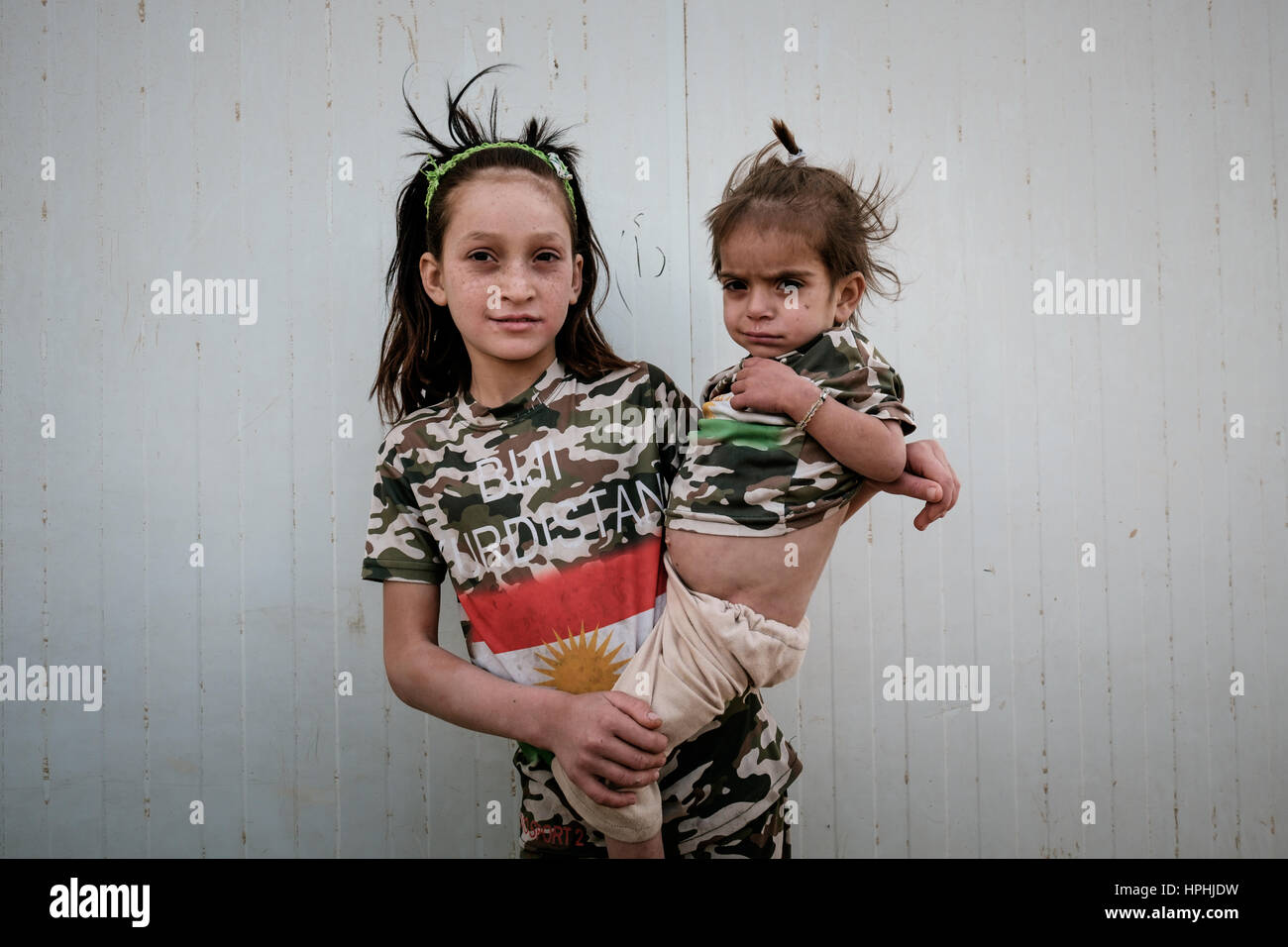 Ragazza di rifugiati che porta il suo bambino malato la sorella di indossare magliette con lo slogan BIJI KURDISTAN (Evviva il Kurdistan) Sinjar Mountain Iraq Foto Stock