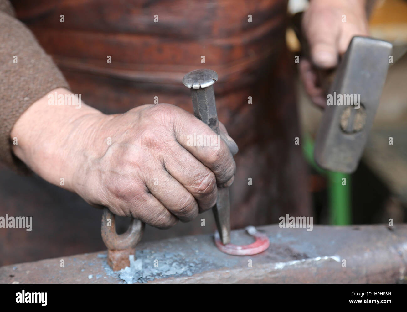 Mano anziano fabbro che utilizza un ferro da stiro awl ed un martello su un grande incudine Foto Stock